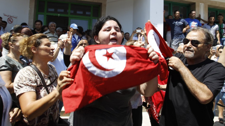 Assassinated Tunisian opposition politician Mohamed Brahmi's daughter Balkis (C) holds a Tunisian flag as she mourns his death in Tunis