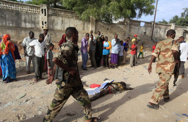 Somali police walk past the body of a suspected al Shabaab militant who was killed in an explosion while attempting to plant a roadside bomb in the capital Mogadishu