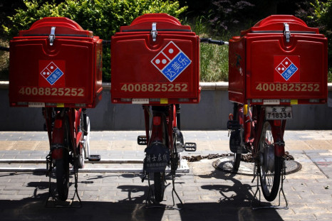 Three electric bicycles used to deliver Domino's Pizzas can be seen parked on the footpath.