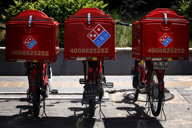 Three electric bicycles used to deliver Domino's Pizzas can be seen parked on the footpath.