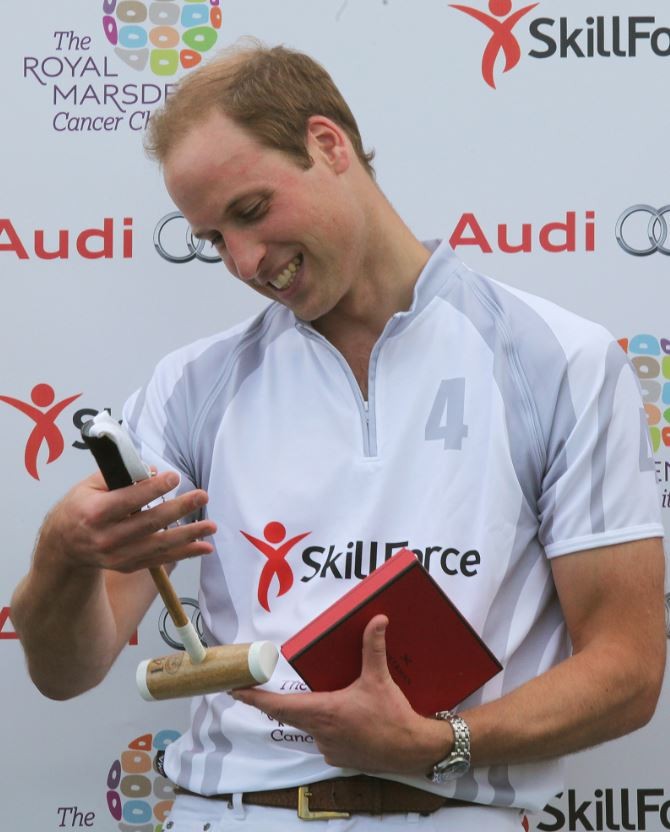 Prince William holds a childs polo mallett, given to him after competing in a charity polo match at Coworth Park, southern England August 3, 2013.