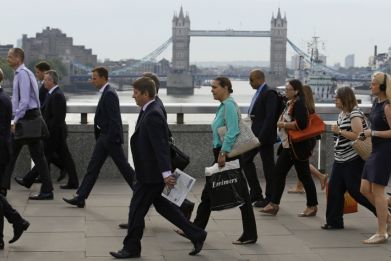 Commuters walk across London Bridge to the City of London