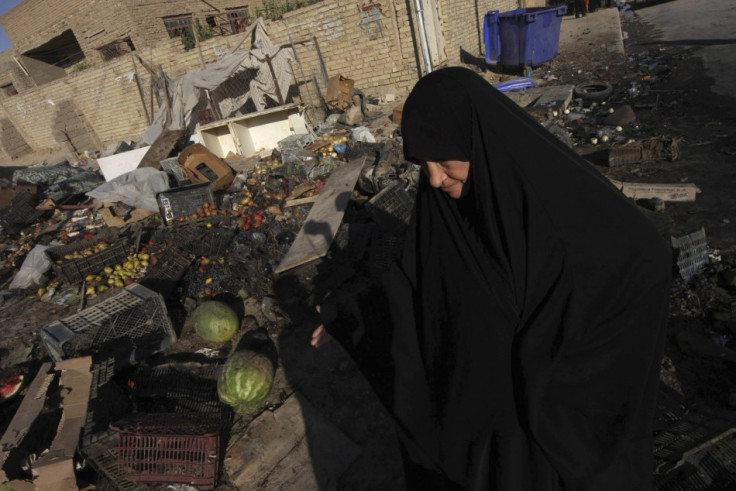 A woman walks past the site of a car bomb attack in Kerbala, 110 km (70 miles) south of Baghdad