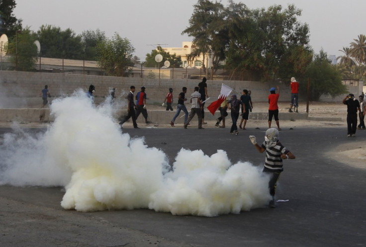 A protester is covered in a cloud of tear-gas during clashes with riot police in the village of Shakhoora, west of Manama,