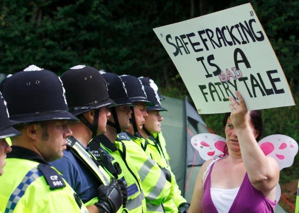 A demonstrator holds a sign that reads "Safe Fracking Is A Bad Fairy Tale" as police escort a lorry to a site run by Cuadrilla Resources, outside the village of Balcombe in southern England (Photo: Reuters)
