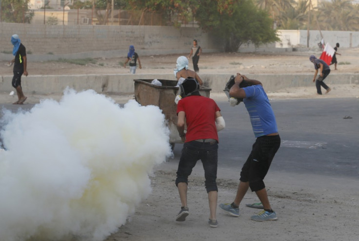 Protesters put on masks as riot police fire tear gas canisters at them during clashes in the village of Shakhoora