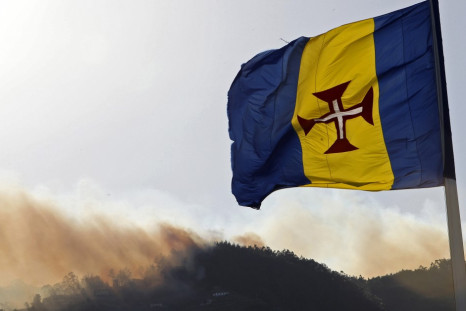 Fires rage in Madeira in July behind the regional flag.