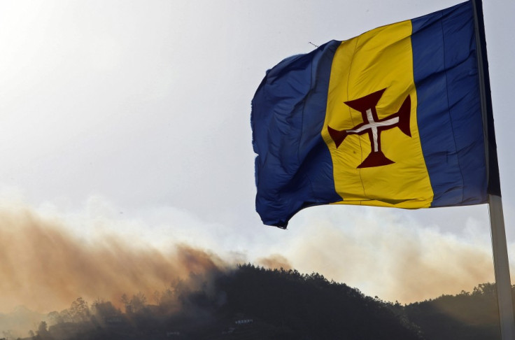 Fires rage in Madeira in July behind the regional flag.