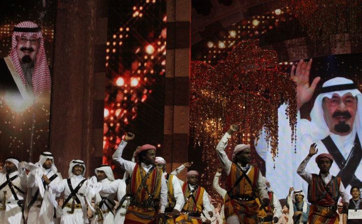 Performers raise their swords in front of a portrait of Saudi King Abdullah