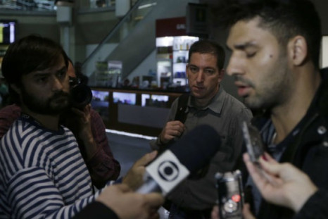 US journalist Glenn Greenwald (C) looks on as his partner David Miranda (R) talks with the media after arriving at Rio de Janeiro's International Airport August 19, 2013.