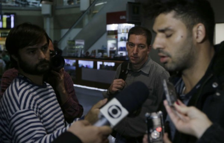 US journalist Glenn Greenwald (C) looks on as his partner David Miranda (R) talks with the media after arriving at Rio de Janeiro's International Airport August 19, 2013.