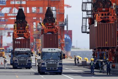 Workers load containers from trucks onto a cargo ship at a port in Tokyo