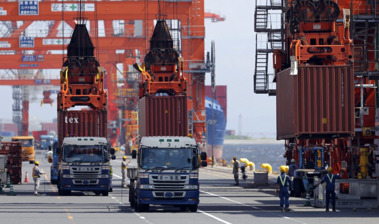 Workers load containers from trucks onto a cargo ship at a port in Tokyo