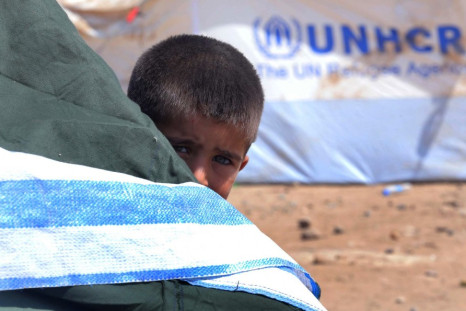 A Syrian refugee boy peeps behind a tent at the Quru Gusik refugee camp on the outskirts of Arbil in Iraq's Kurdistan region