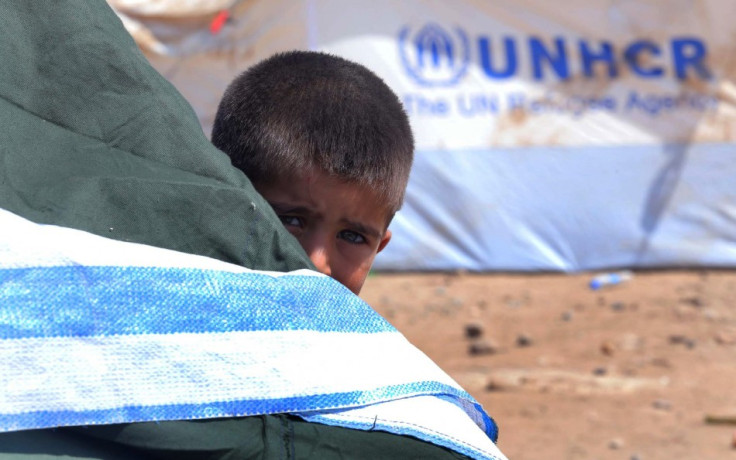 A Syrian refugee boy peeps behind a tent at the Quru Gusik refugee camp on the outskirts of Arbil in Iraq's Kurdistan region