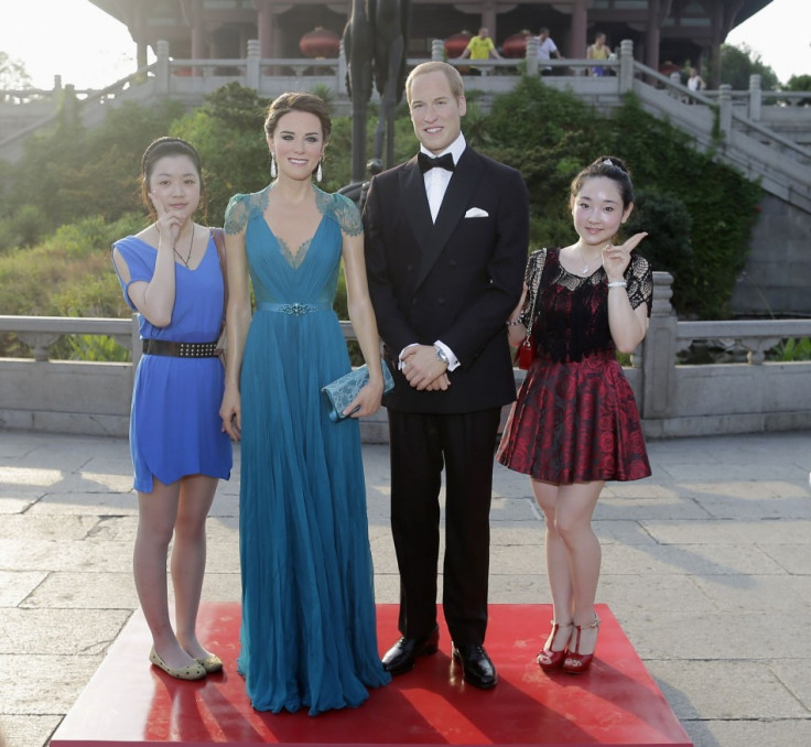 Visitors pose for photographs next to Madame Tussauds' wax figures Prince William and Catherine (2nd L), Duchess of Cambridge, in front of the Yellow Crane Tower during a promotional event in Wuhan, Hubei province August 13, 2013. The fifteenth Madame Tus