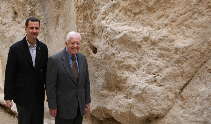 Syria's President Bashar al-Assad (L) walks with former U.S. president Jimmy Carter, at mountain pass of St. Taqla convent, during a visit to the historic city of Maaloula,