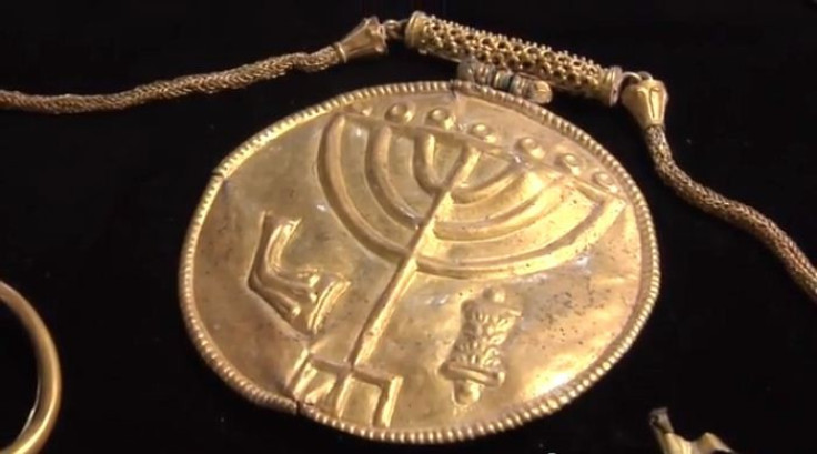 The gold medallion hangs from a gold chain and has the symbols of a menorah (centre), a shofar (left) and a Torah scroll (right) etched into it. (YouTube Video Screenshot/Hebrew University)
