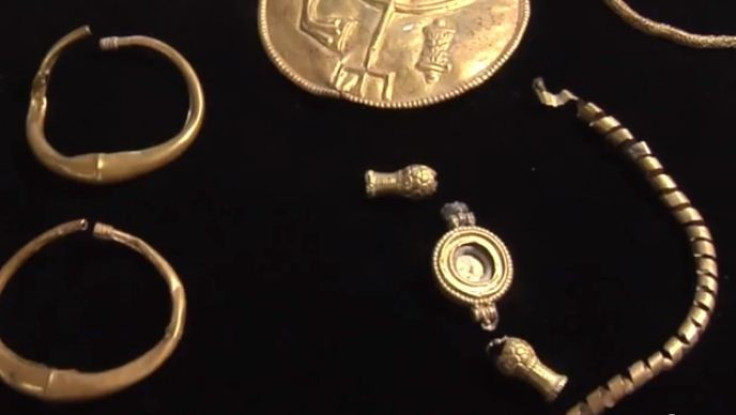A pair of large gold earrings, a gold-plated silver hexagonal prism and a silver ingot were found along with the coins. (YouTube Video Screenshot/Hebrew University)