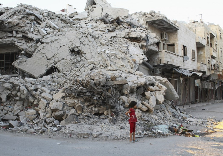 A girl stands in front of a building damaged by what activists said was shelling by forces loyal to Syria's President Bashar al-Assad