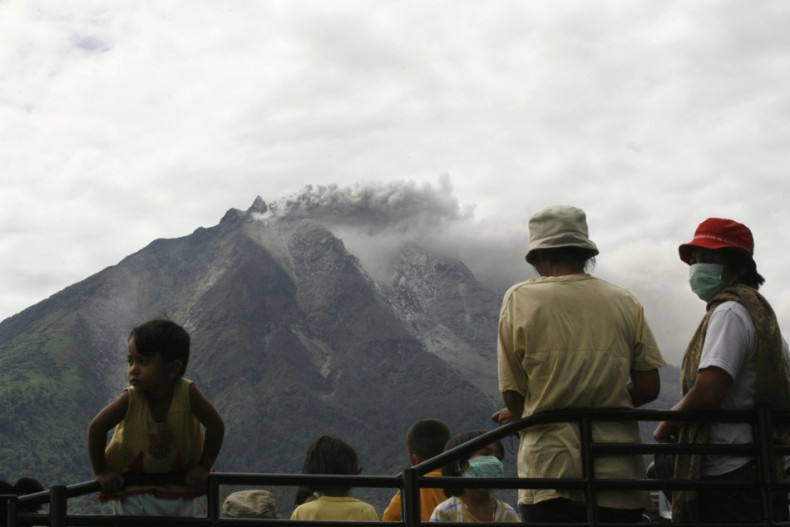 Villagers wait to be taken to safety as Mount Sinabung sends ash and smoke high into the air.