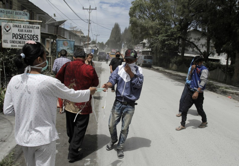 A paramedic hands out masks to people fleeing the mount Sinabung eruption.