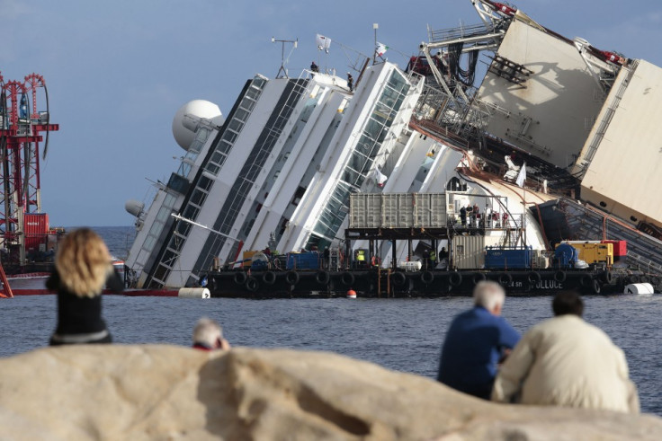 People look on as the capsized cruise liner Costa Concordia lies on its side next to Giglio Island