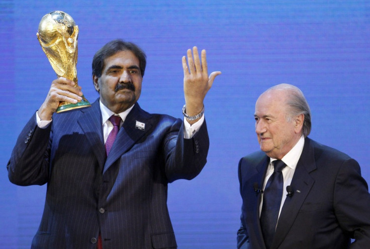 Qatar's Emir Sheikh Hamad bin Khalifa al Thani (L) holds up a copy of the World Cup he received from FIFA President Sepp Blatter