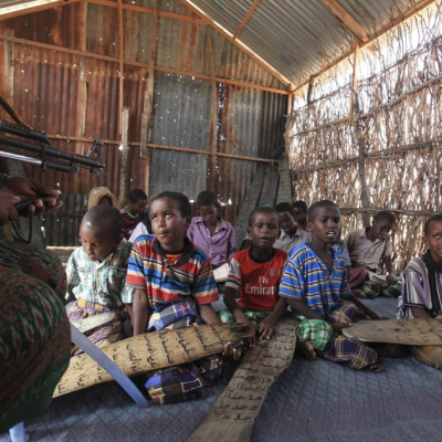 A teacher at a school in Dhusamareeb, central Somalia, takes a class while armed with an AK 47 to defend against Islamist Al-Shabaab fighters