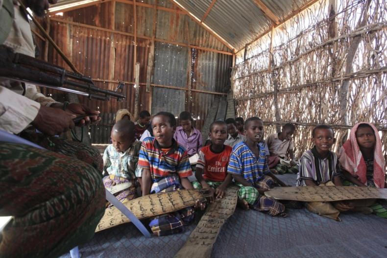 A teacher at a school in Dhusamareeb, central Somalia, takes a class while armed with an AK 47 to defend against Islamist Al-Shabaab fighters