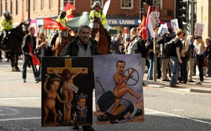 A protester holds paintings depicting caricatures of  David Cameron during the protest (Reuters)