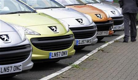 A man passes cars on a showroom forecourt in west London