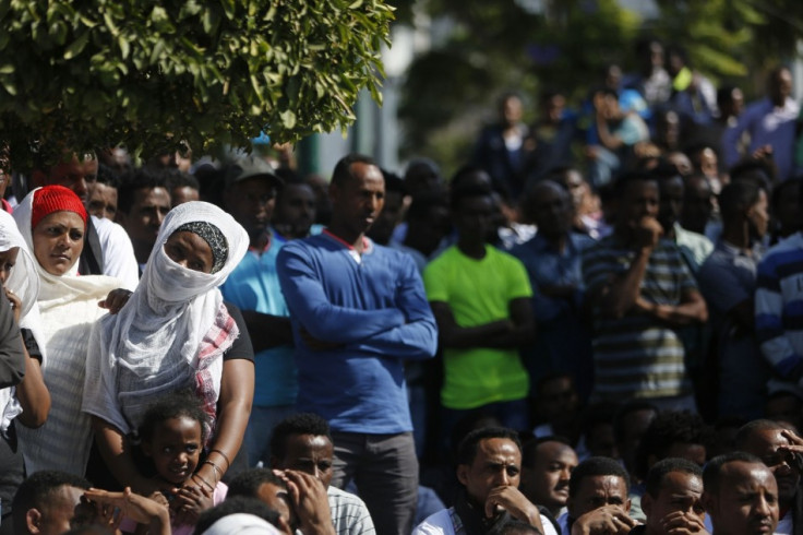 African migrants watch a memorial service for the deaths of hundreds of migrants in last week's Lampedusa boat disaster, in Tel Aviv