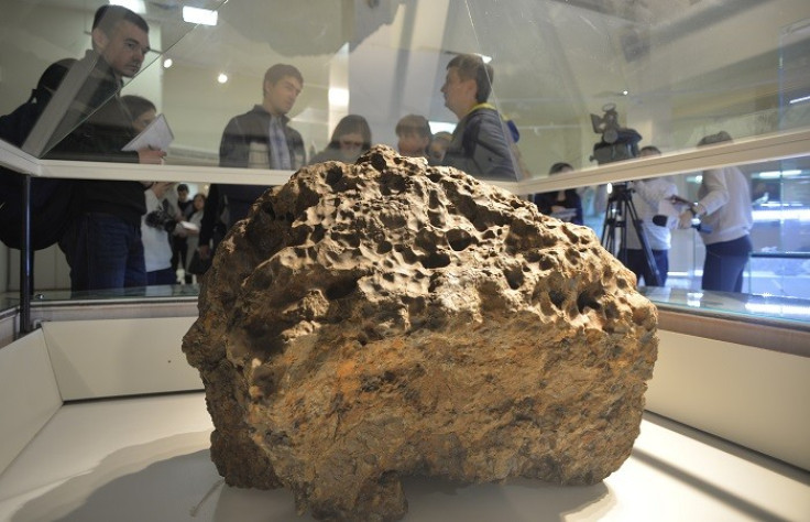 Reporters gather around a piece of a meteorite that crashed in Russia (Reuters)
