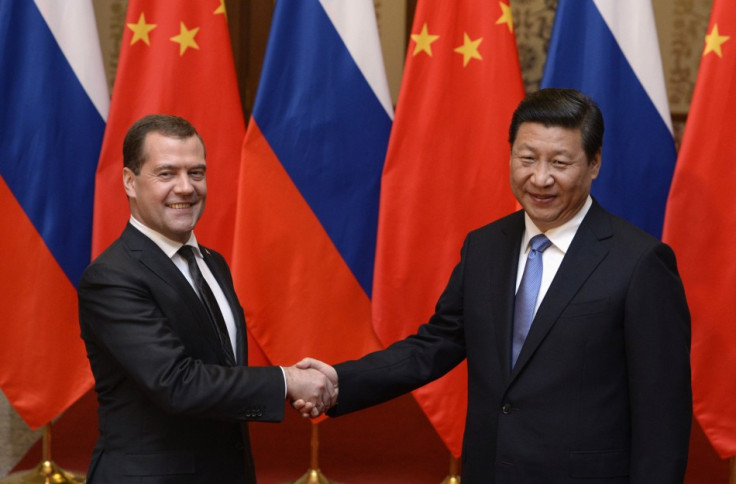 Russian Prime Minister Dmitry Medvedev shakes hands with Chinese President Xi Jinping