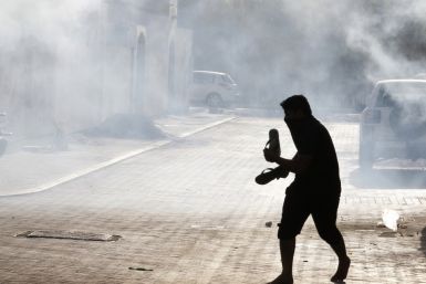 A protester runs to take cover from tear gas fired by riot police during clashes in the village of Maqusha, west of Manama