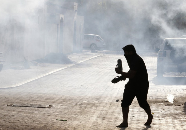 A protester runs to take cover from tear gas fired by riot police during clashes in the village of Maqusha, west of Manama A protester runs to take cover from tear gas fired by riot police during clashes in the village of Maqusha, west of Manama