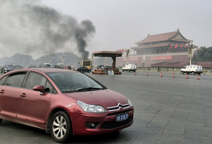 Vehicles travel along Chang'an Avenue as smoke raises in front of a portrait of late Chinese Chairman Mao Zedong at Tiananmen Square in Beijing