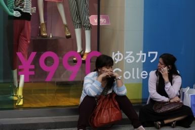 Women sit in front of a clothing store in Tokyo