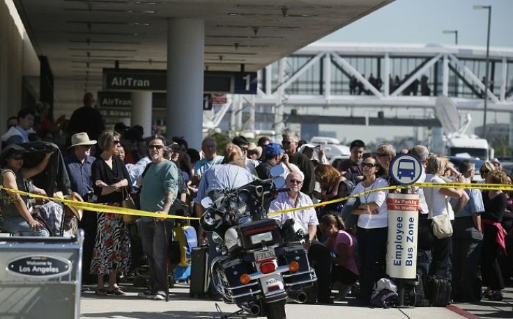 Delayed passengers stand behind a police cordon after a shooting incident at Los Angeles airport. (Picture: Reuters)