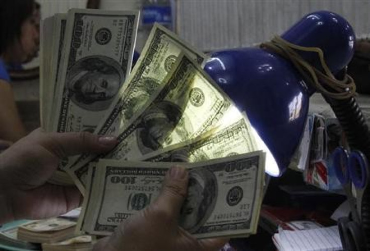 An employee inspects U.S. dollar bills before changing it to Philippine Pesos inside a money changer in Manila