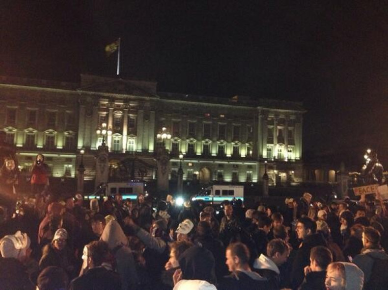 Anonymous protestors congregate in front of Buckingham Palace
