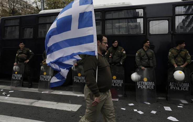 A man holds a Greek flag in front of riot policemen during a military parade to mark Greece's Independence Day in Athens March 25, 2013. (Photo: Reuters)