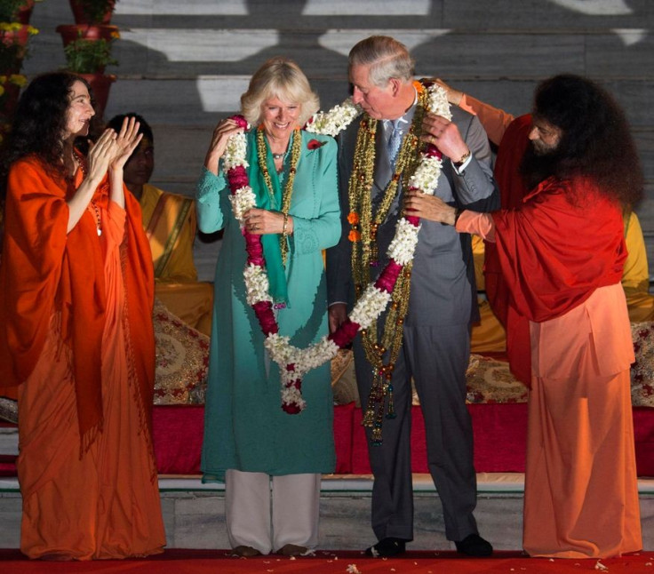 By being greeted in common garland with Prince Charles, Camilla can't resist blushing. (Photo: Reuters)