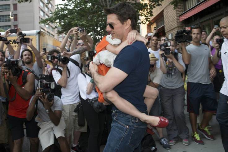 Actor Tom Cruise carries his daughter Suri past a group of photographers.