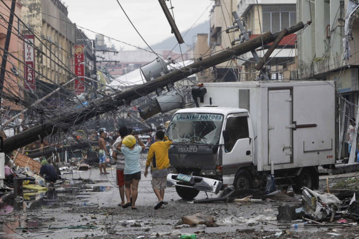 Survivors walk under a fallen electric post in battered Tacloban city
