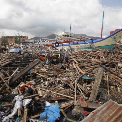 A fishing boat which slammed into damaged houses lie atop debris after super Typhoon Haiyan battered Tacloban city, central Philippines November 10, 2013.  One of the most powerful storms ever recorded killed at least 10,000 people in the central Philippi