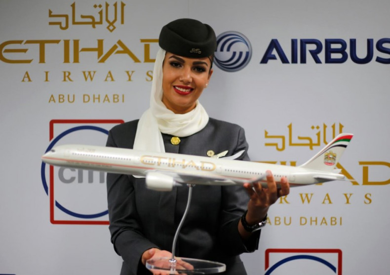 A flight attendant of Etihad Airways holds a model of the Airbus A350 during the Dubai Airshow. (Reuters)