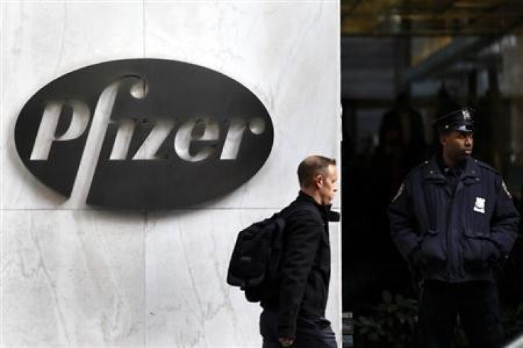 A man walks past the Pfizer logo next to a New York Police Officer standing outside Pfizer's world headquarters in New York November 5, 2013.
