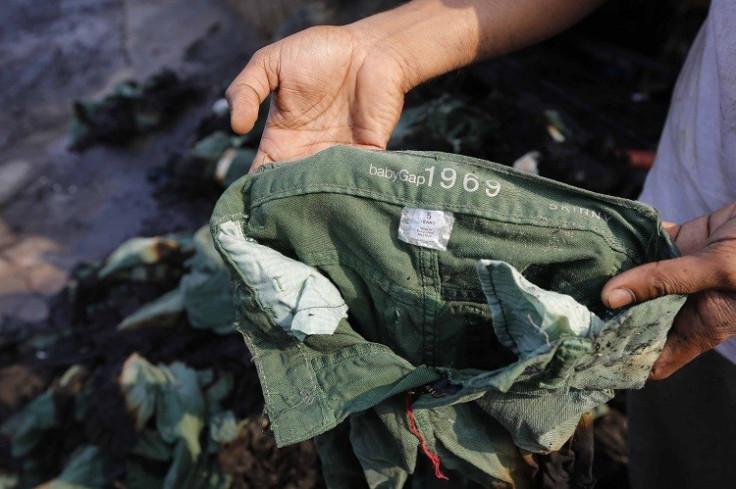 An employee shows the brand of a burnt clothing item in front of a Standard Group garment factory which was on fire in Gazipur November 29, 2013. (Photo: Reuters)